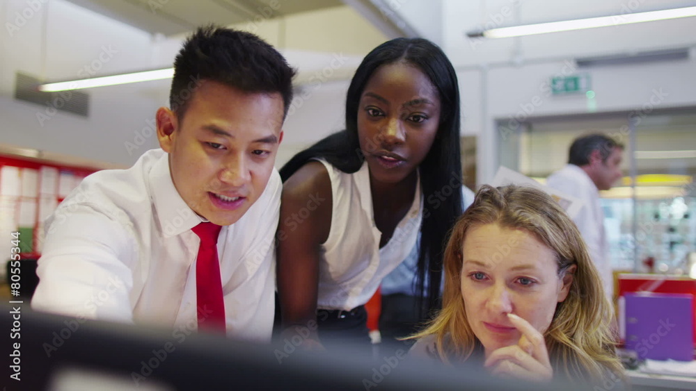 Attractive diverse business group in modern office looking at a computer screen
