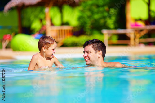 father and son having fun in outdoor pool, summer vacation
