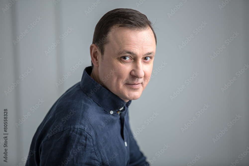 Obraz premium Man sitting with a slight smile and looking at the camera.