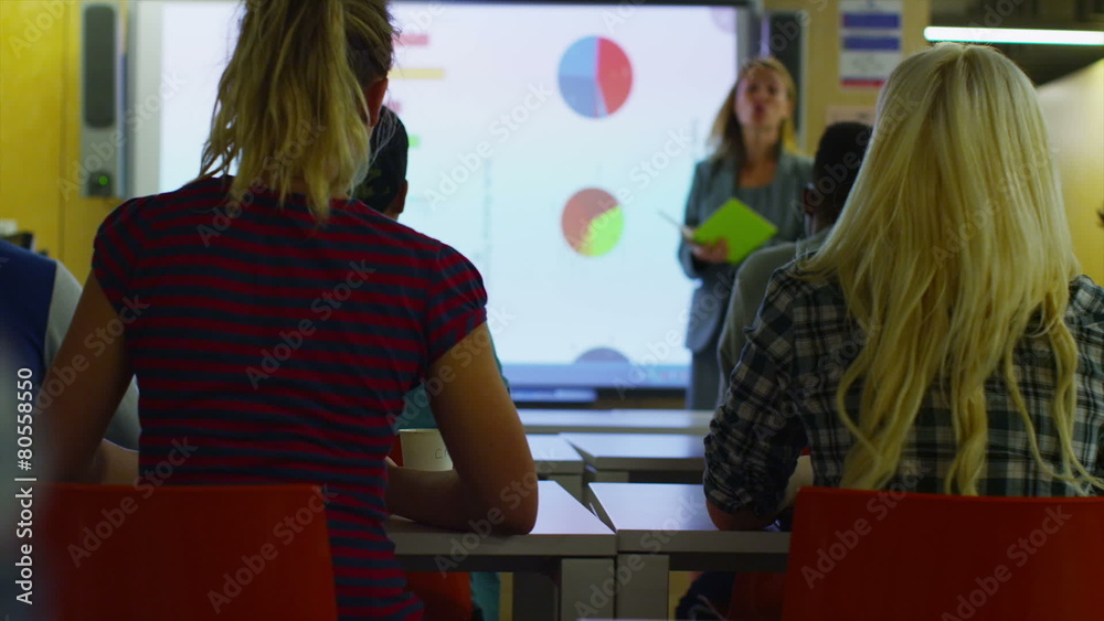 Attractive young teacher in class, explaining a subject to her students. Attractive young teacher in class, explaining a subject to her students.