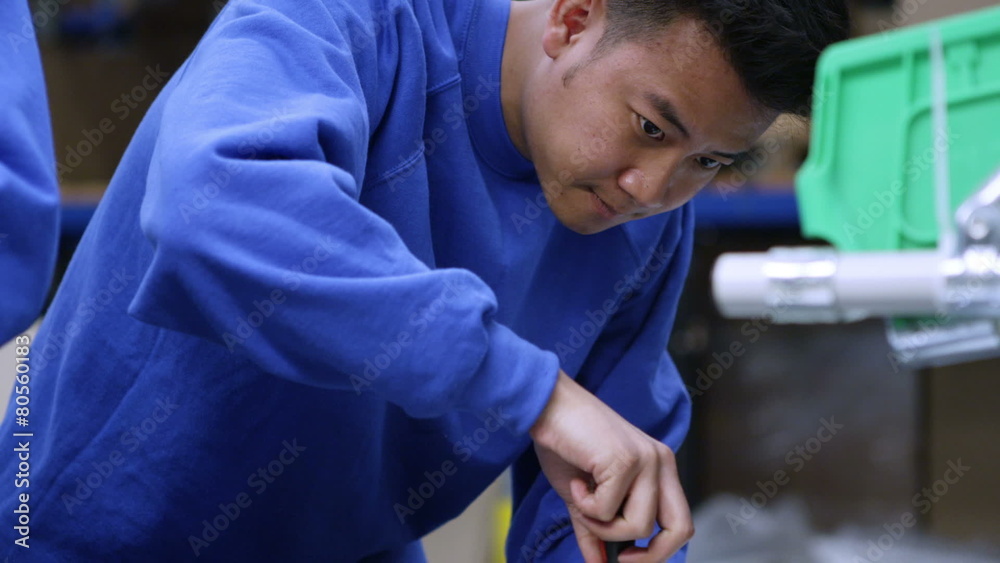 Young Asian factory worker concentrating on his work
