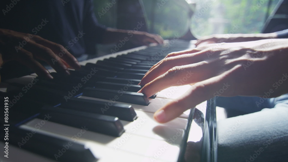 Close up of male hands playing the piano in natural, direct light