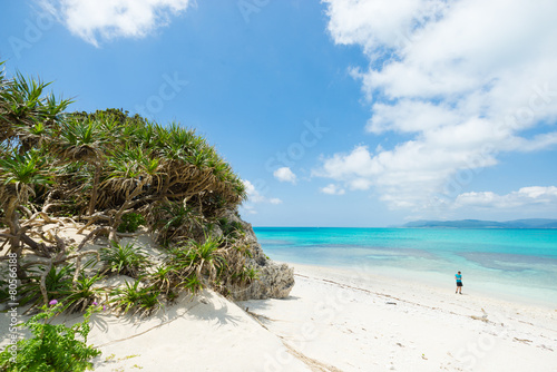 Man overlooking view of tropical white sand beach paradise lagoon full of healthy coral reef in Okinawa