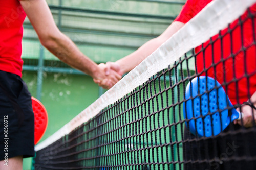 Friends shaking hands in paddle tennis field © chandlervid85