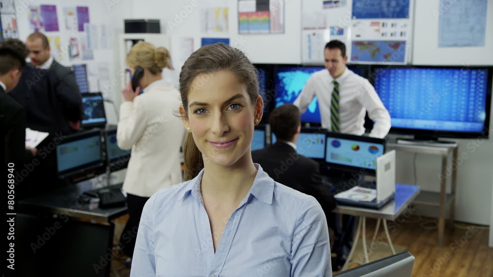 Portrait of a successful financial trader with her colleagues in the background. Portrait of a successful financial trader with her colleagues in the background.