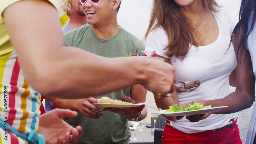 Happy young man cooking and serving barbecue food to his friends