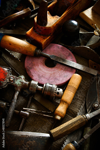 Many old working tools (axe, drill, saw and others) on a wooden