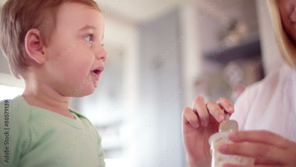 Baby boy eating some food his mother is feeding him Baby boy eating some food his mother is feeding him