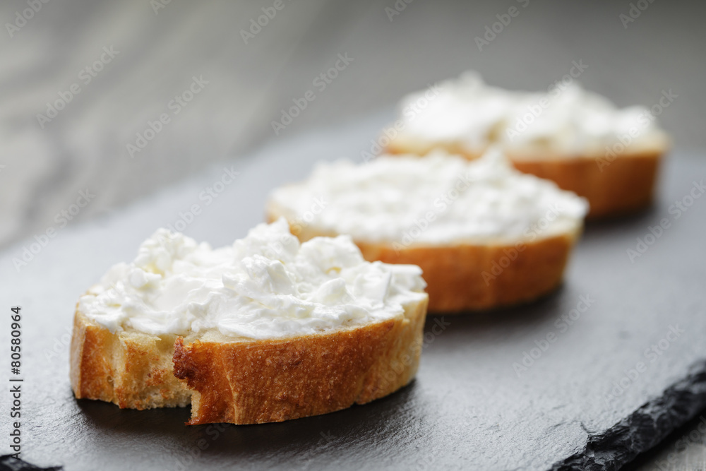 crunchy baguette slices with cream cheese on slate board crunchy baguette slices with cream cheese on slate board