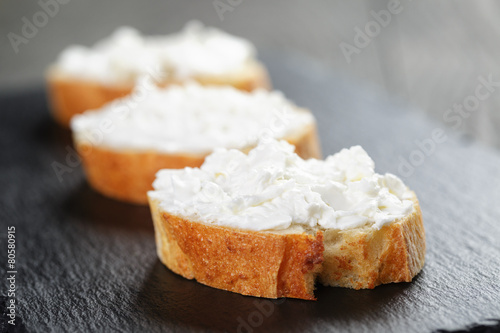 crunchy baguette slices with cream cheese on slate board