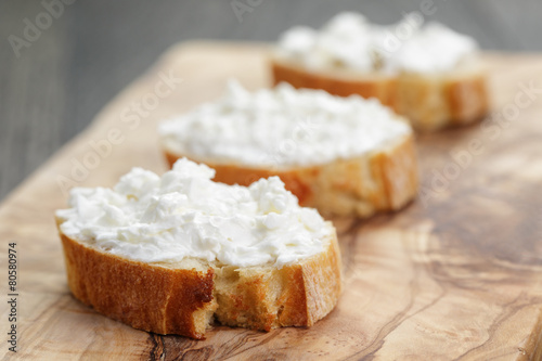 crunchy baguette slices with cream cheese on olive board