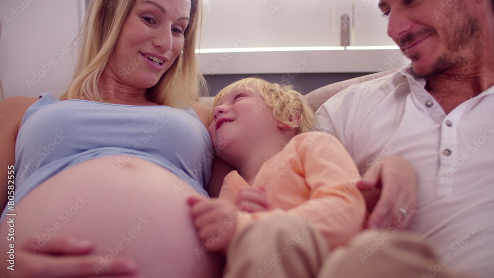 Little boy on the couch with dad and pregnant mom Little boy on the couch with dad and pregnant mom