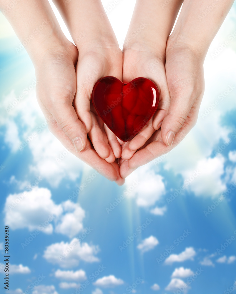 Family concept - mother's hands holding child hands with heart