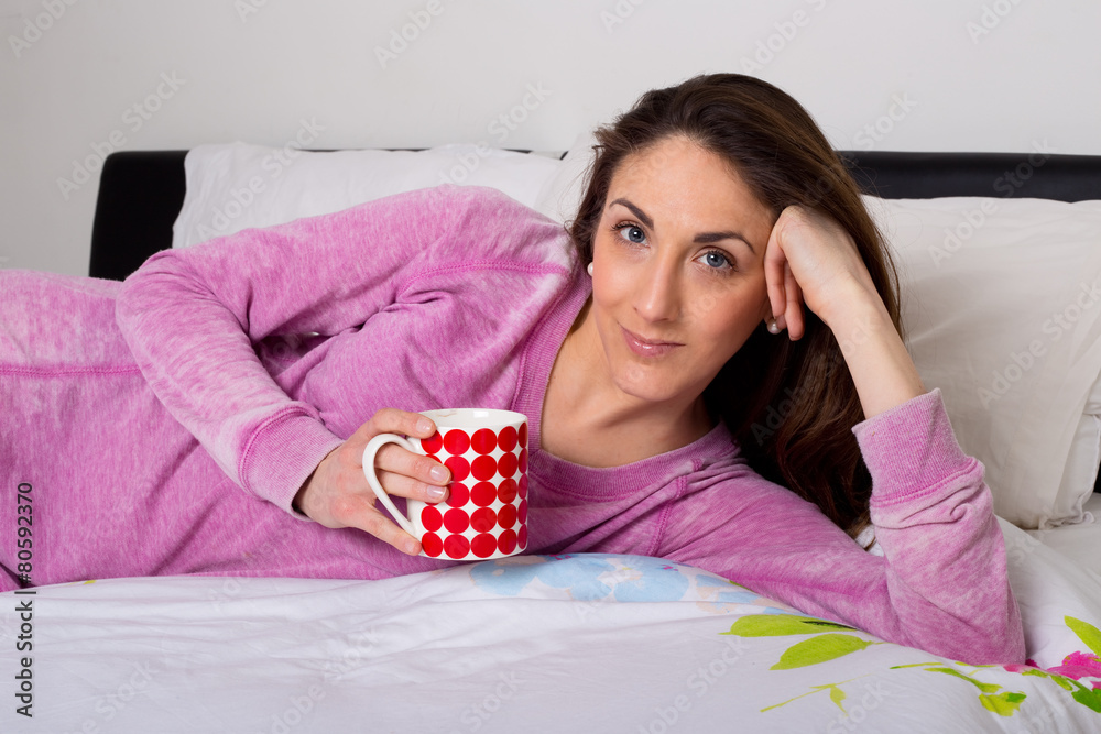 young woman enjoying a hot drink in bed young woman enjoying a hot drink in bed
