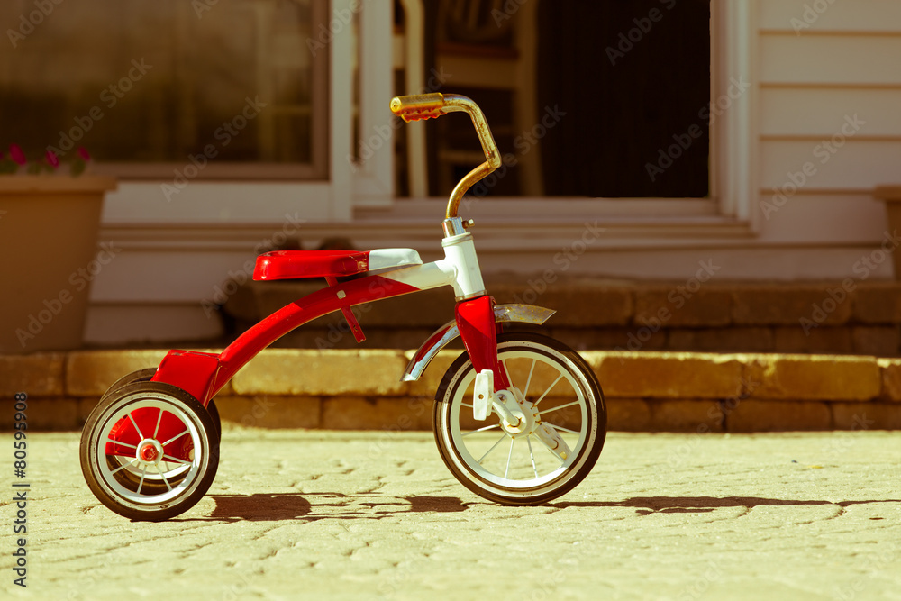 Obraz premium Child's rusted red tricycle standing ready