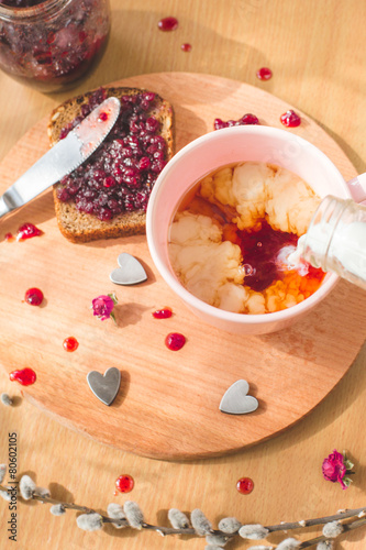 tea with pouring milk, homemade bread with blackcurrant jam