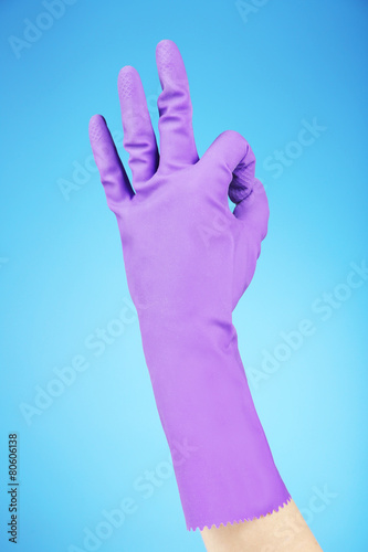Rubber glove on hand  on blue background