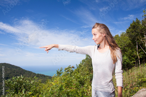 girl stands on a hilltop points into the distance