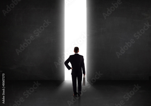 Business person looking at wall with light tunnel opening