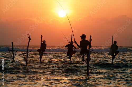 Silhouettes of the traditional fishermen at the sunset not far f