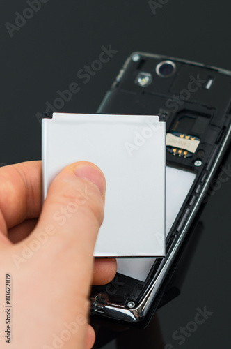 Male hand inserting battery to mobile phone.