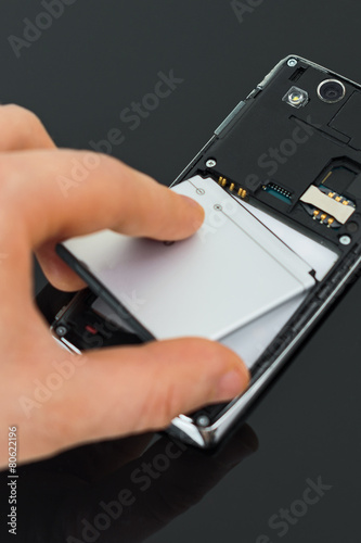 Male hand inserting battery to mobile phone.
