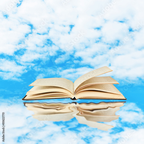 Opened book on sky background © Africa Studio