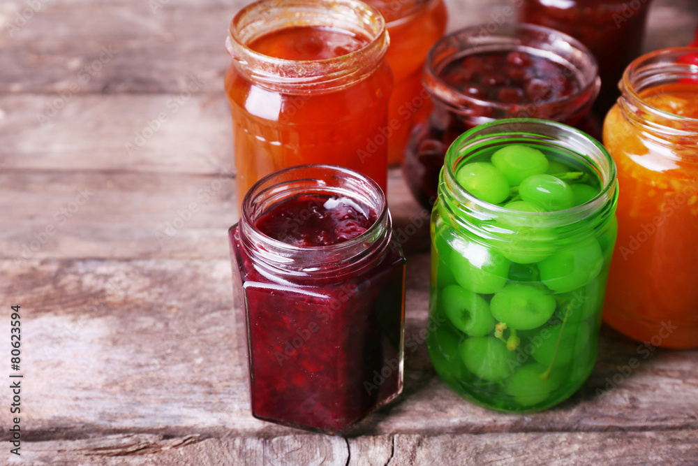 Homemade jars of fruits jam on rustic wooden background Homemade jars of fruits jam on rustic wooden background