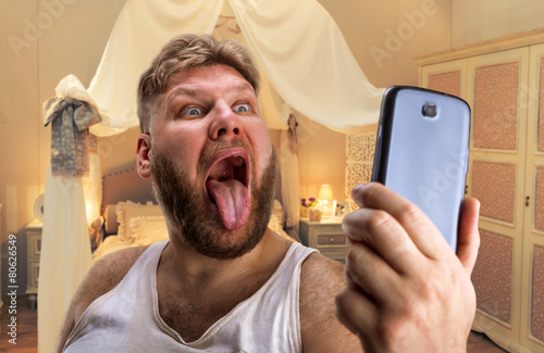 Adult man takes selfie showing his tongue
