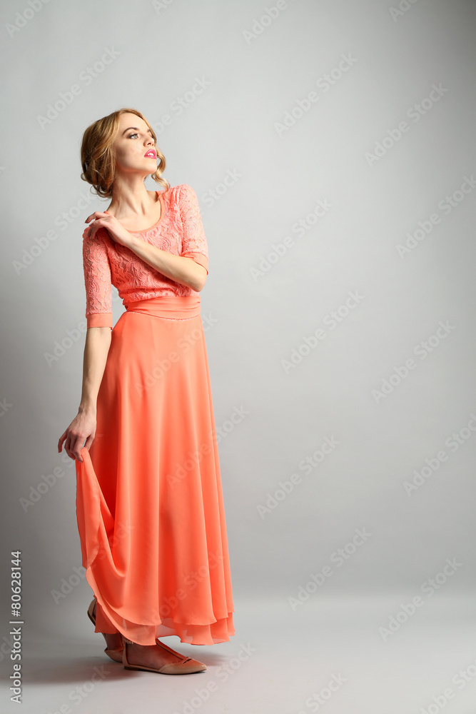 Beautiful young woman in color dress posing on light background Beautiful young woman in color dress posing on light background