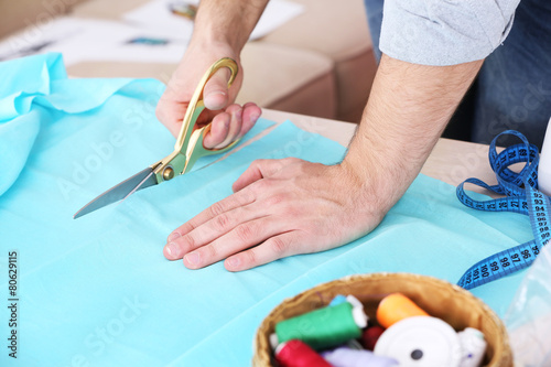 Male dressmaker cut fabric on table