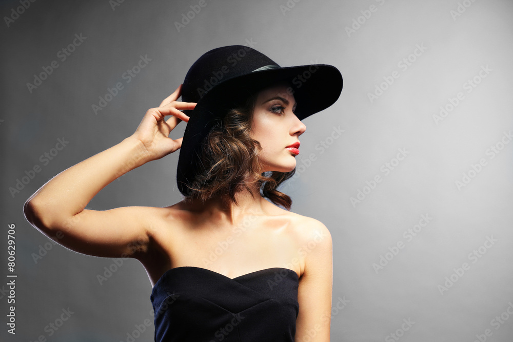 Portrait of beautiful model in black dress and hat on gray background Portrait of beautiful model in black dress and hat on gray background
