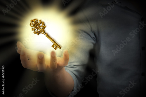 business person holding shining key