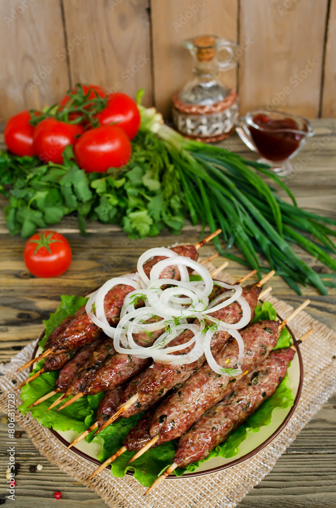 Grilled kebabs on wooden skewers and fresh vegetables Grilled kebabs on wooden skewers and fresh vegetables