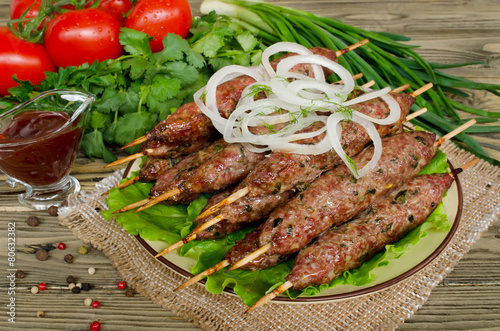 Grilled kebabs on wooden skewers and fresh vegetables