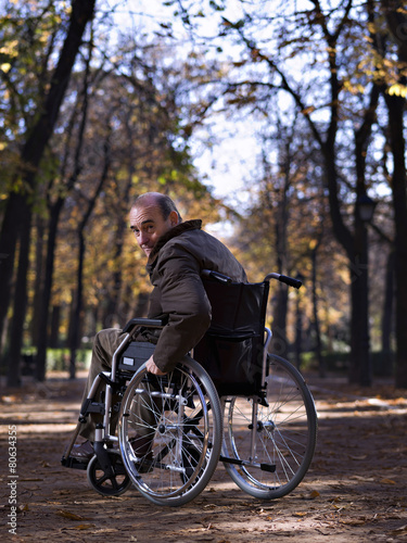 Mature man in wheelchair, in a park, one autumn day