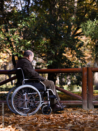 Mature man in wheelchair, in a park, one autumn day