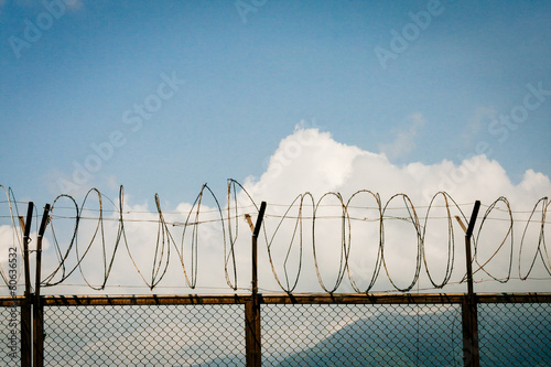 barbed wire fence razor blue sky clouds