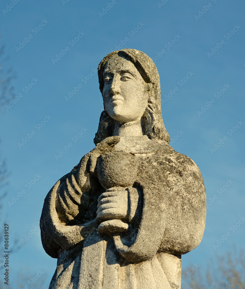 Old stone statue of a woman with a cup for Holy Communion on the