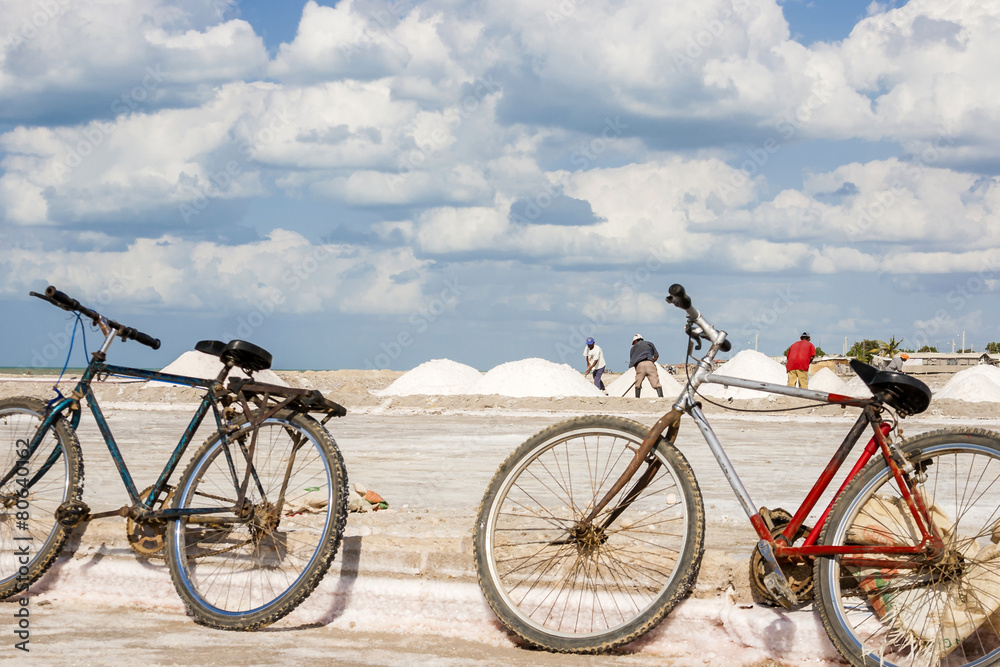 Obraz premium Viejas bicicletas oxidadas y hombres trabajando en las piscinas de evaporación en la mina de sal a cielo abierto de Manaure en la Guajira en Colombia