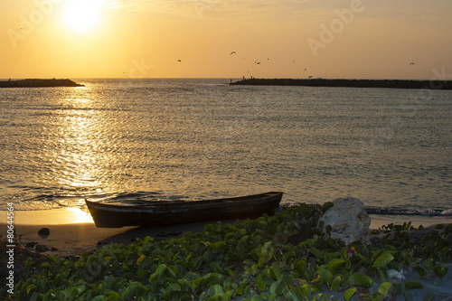 Barca de madera vacía junto al mar al atardecer en una playa de Cartagena de Indias en Colombia © anamejia18