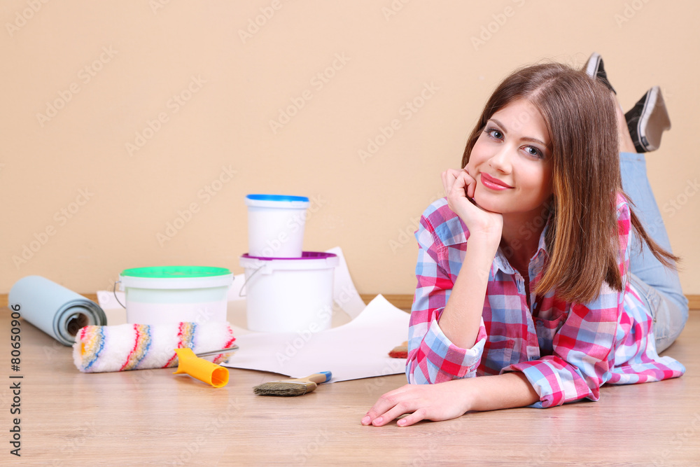 Beautiful girl lying on floor with equipment for painting wall Beautiful girl lying on floor with equipment for painting wall