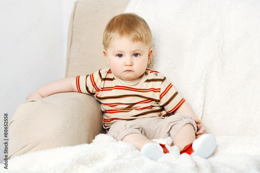 Cute baby boy on sofa, on light background Cute baby boy on sofa, on light background