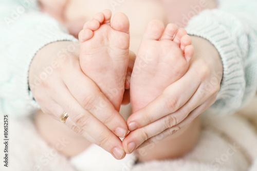 Newborn baby feet on female hands, close-up © Africa Studio