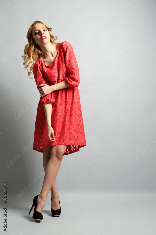 Beautiful young woman in color dress posing on light background Beautiful young woman in color dress posing on light background