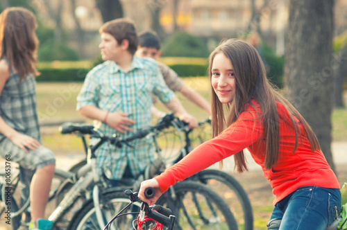 Teenage girl having fun on bicycles with her friends in the park