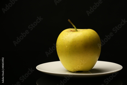 Apple on saucer on black background