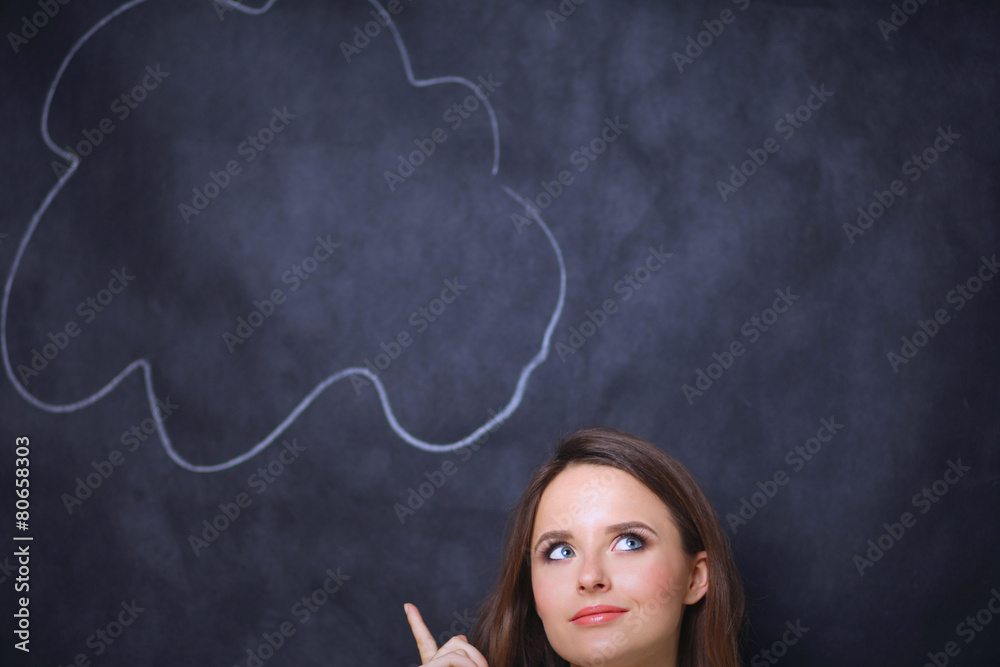 portrait of attractive girl thinking and pointing  up to blank