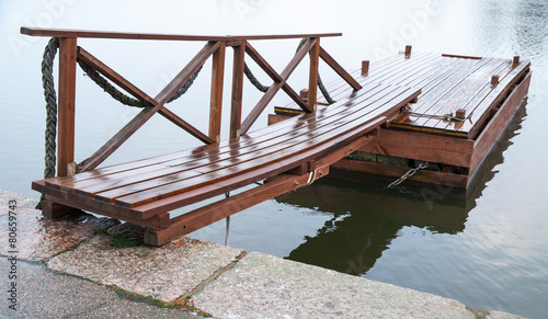 Shining wet wooden floating pier in still lake water