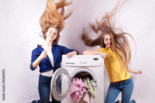 Girl sitting on the washing machine with the laundry for washing